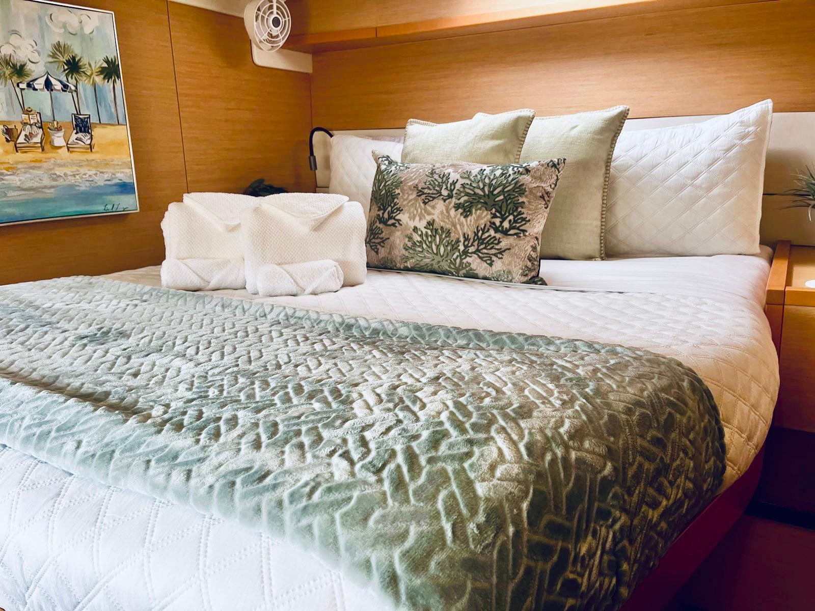 Queen cabin with fresh towels and coral cushions